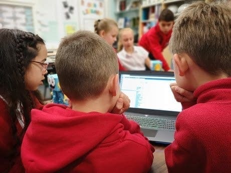 Coding Marty Some students around a laptop writing code with Marty the Robot