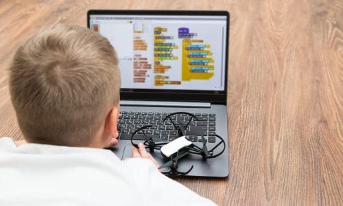 A teenage boy programs a copter drone on a scratch. STEM educati